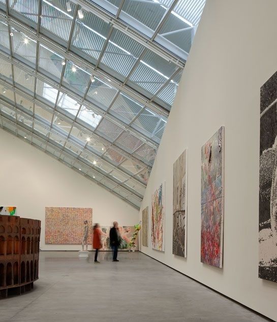 Galleria d’arte illuminata da un grande lucernario con opere esposte
